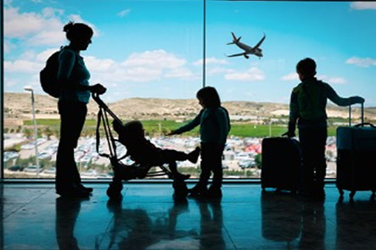 mother-with-kids-and-luggage-looking-at-planes-in-airport 360 x 240